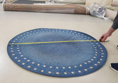 Eingangskontrolle: ein kleiner blauer runder Teppich wird vermessen und auf Verschmutzung untersucht